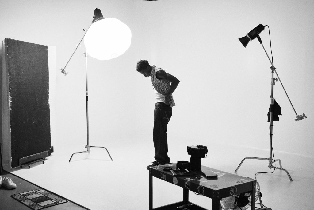 photography studio space with two tripods and two studio lights on them. there is a man between the two tripods